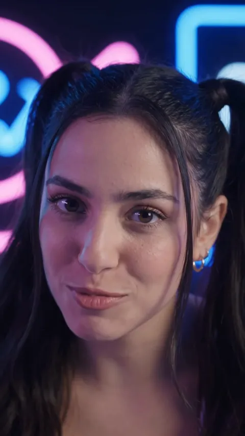 נערה עם צמות על רקע שלטי ניאון ורודים וכחולים — פריים מפרסומת